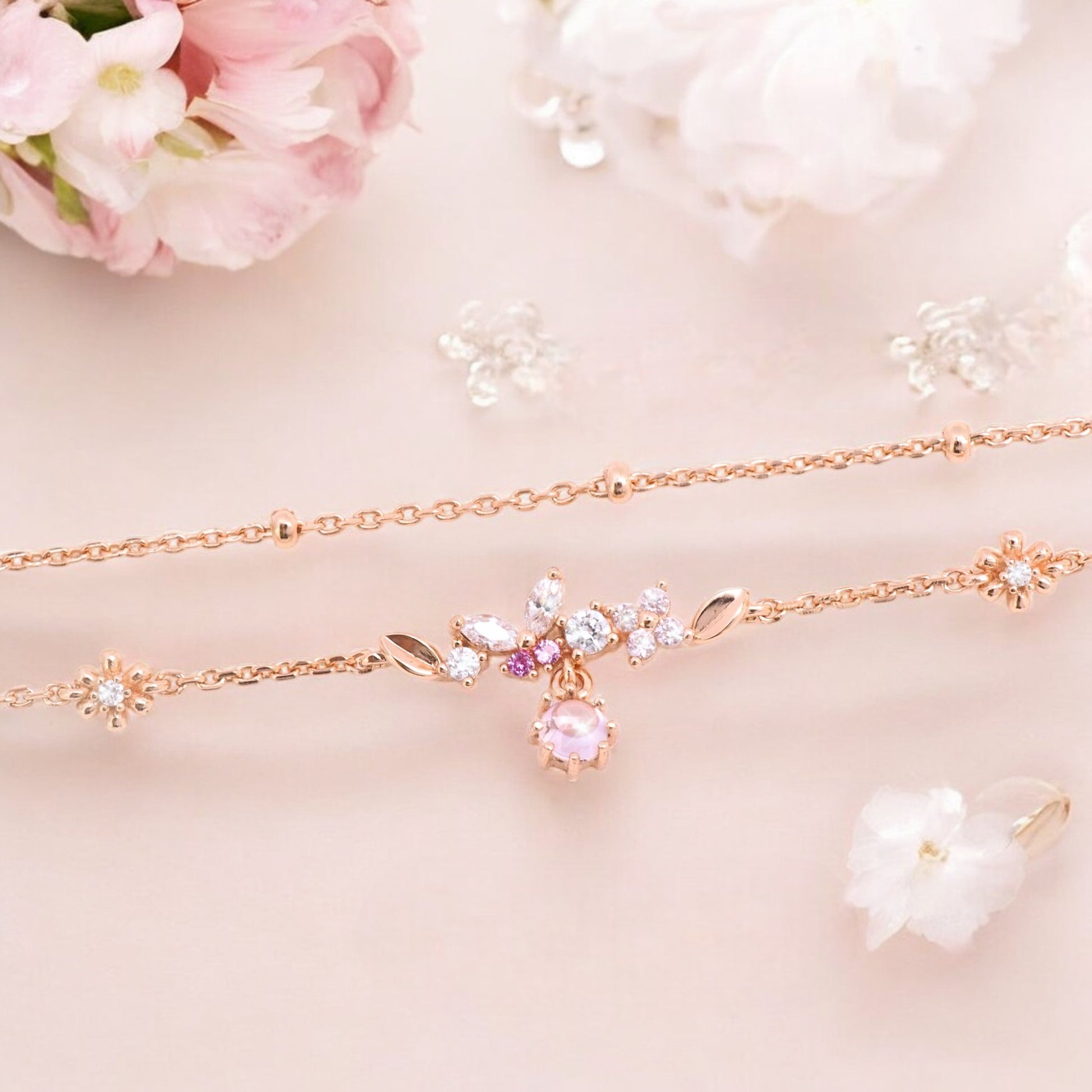 A beautiful rose gold bracelet set with a row of tiny butterfly-shaped zircons and delicate floral decorations. A pink gemstone is set in the center.