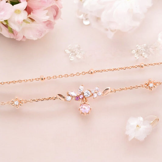 A beautiful rose gold bracelet set with a row of tiny butterfly-shaped zircons and delicate floral decorations. A pink gemstone is set in the center.